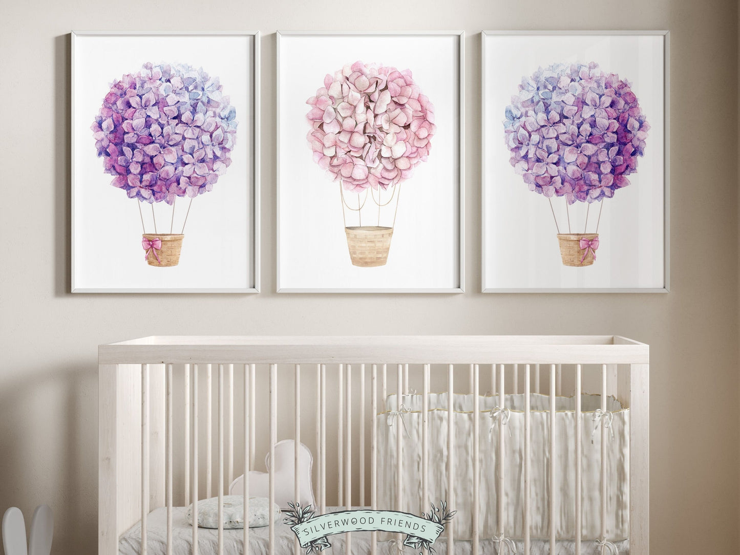 Set of 3 watercolor Hot Air Balloon Prints featuring delightful pink and purple wildflower adorned balloons. A charming addition to your nursery decor and makes an adorable baby shower gift, these prints infuse sweetness and elegance into any space.