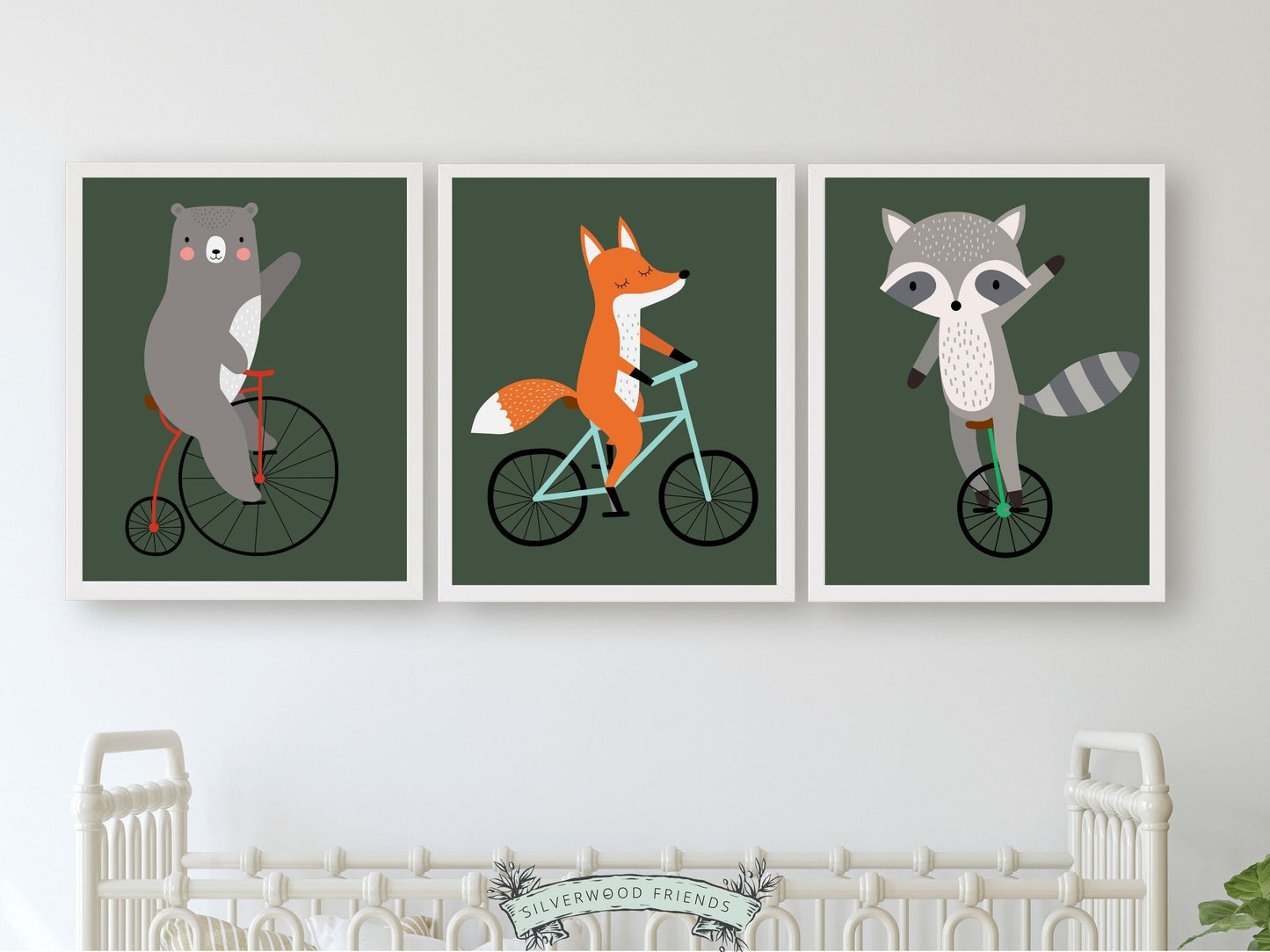 Nursery wall art set of 3 digital prints featuring woodland animals bear, fox and raccoon riding bikes on a dark green background. Perfect for your woodland nursery decor.