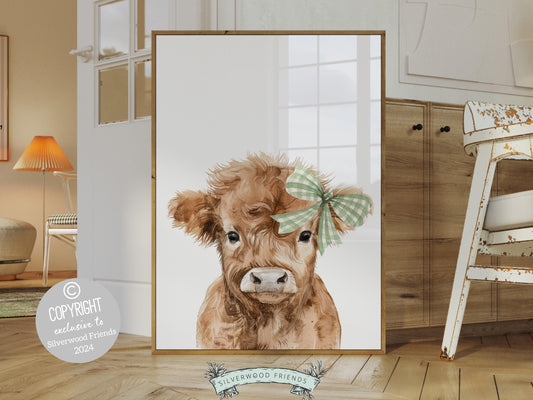 Our Highland Cow Nursery Print features an adorable baby highland cow with a sage green check bow and is set on a white background.