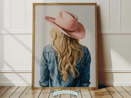 Create a calm and beautiful space with this western cowgirl wall art print, featuring a softly styled portrait of a blonde cowgirl in a pink cowgirl hat, illustrated in a dreamy oil painting style with visible brushstroke texture and warm, rustic tones. This timeless artwork has a rich, canvas-like finish that adds depth, softness, and a charming farmhouse feel to any room.
